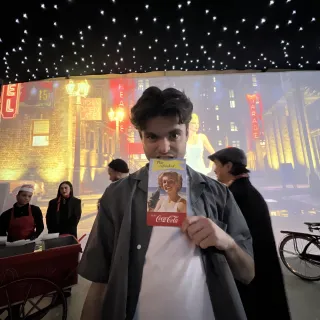 Illia George on set at the Coca-Cola event, holding a promo card