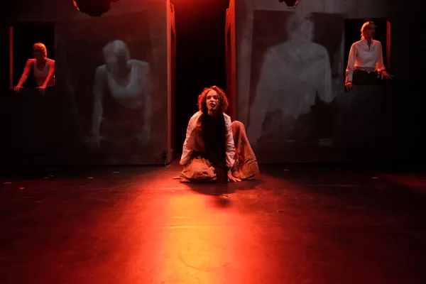 A performer lit in red on stage during Cassandra